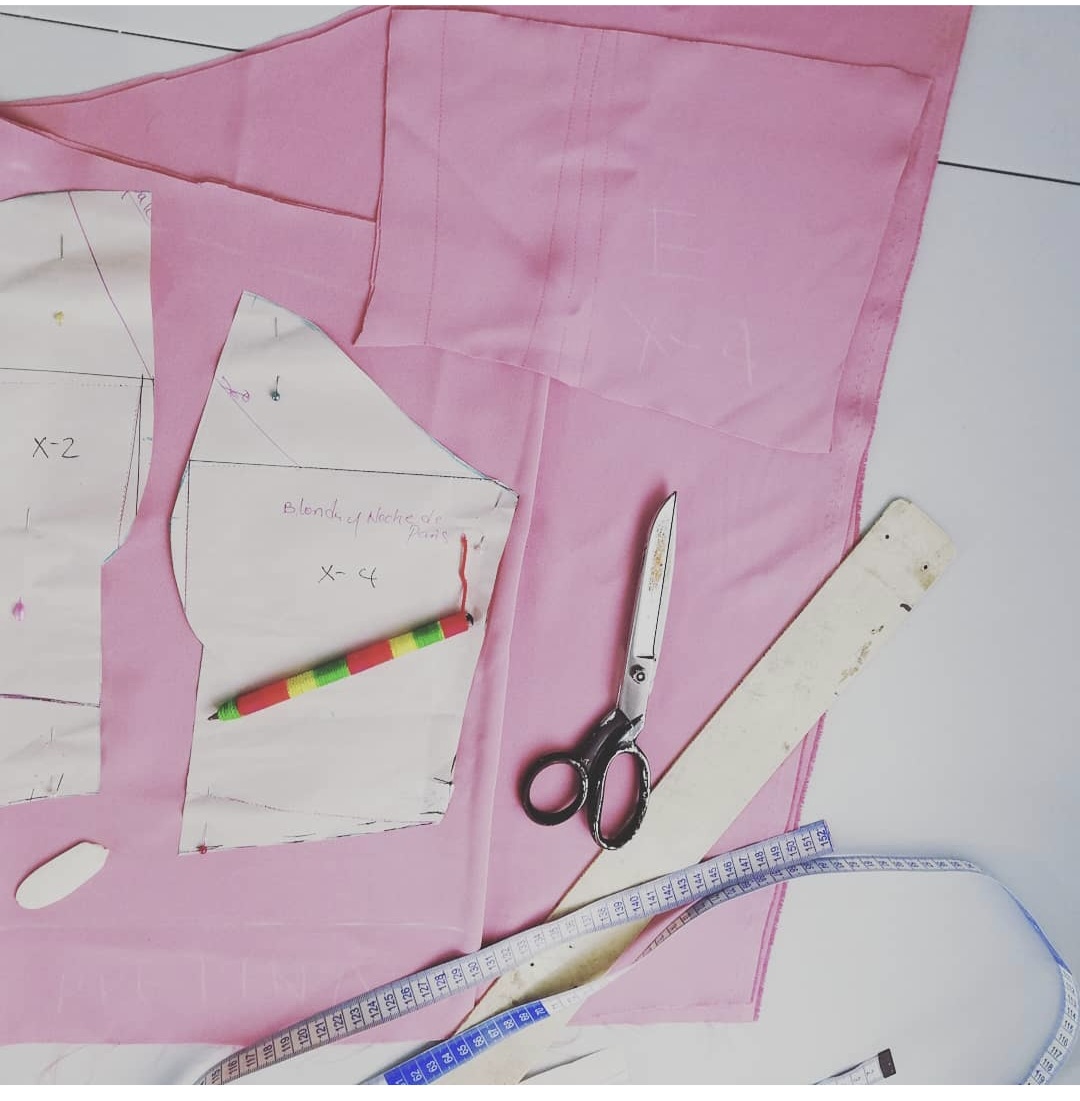 Fabric, scissors and measuring tape on a tailoring worktable